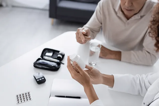 Ärztin berät einen Patienten zu Diabetes-Medikamenten und Blutzuckermessgerät