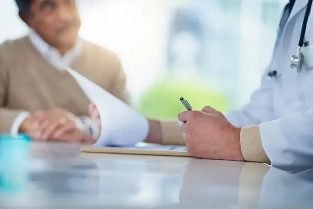 Arzt notiert Befunde im Gespräch mit einem Patienten